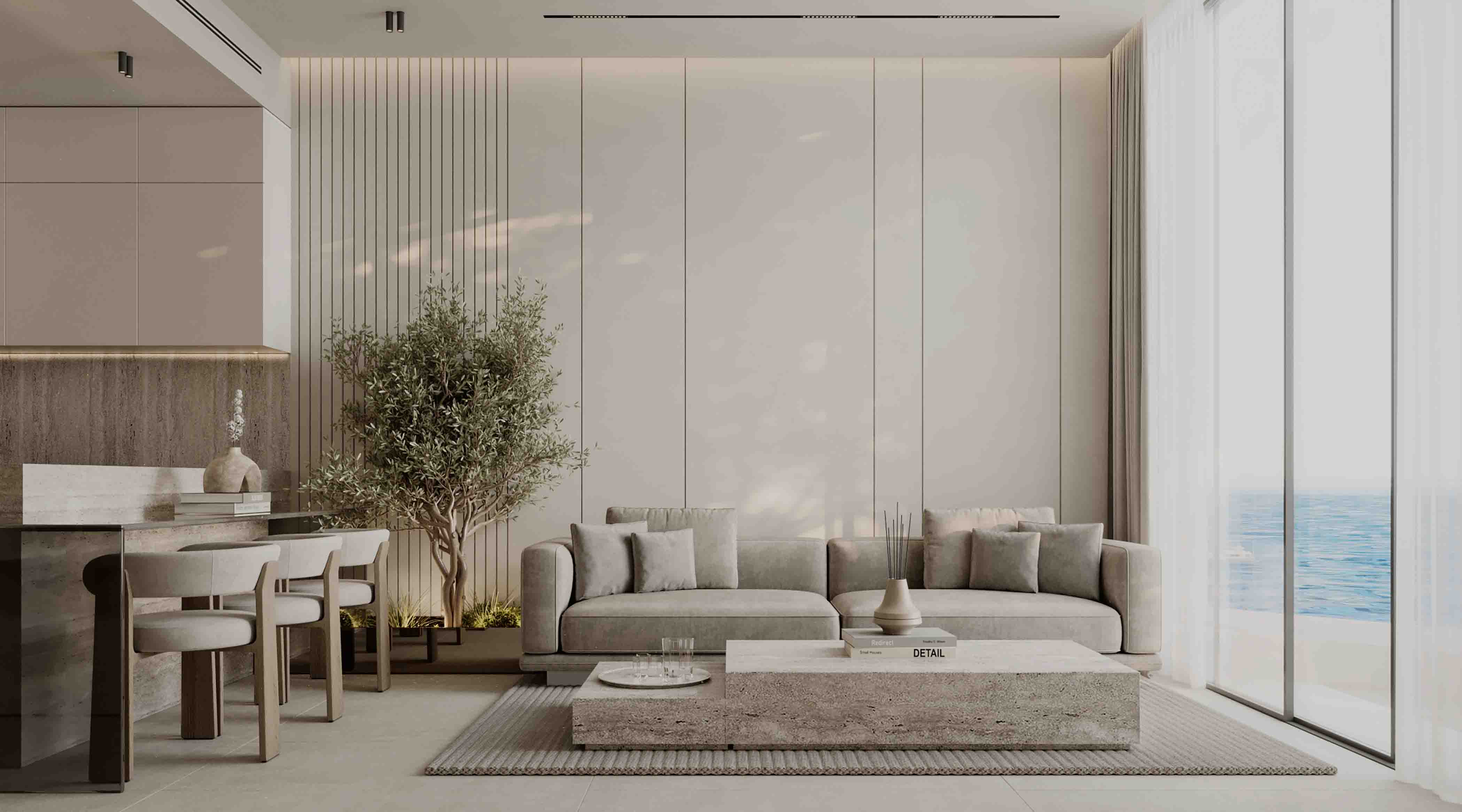 Open-plan living space with soft neutral sofa, stone coffee table and indoor tree by the sea-facing windows.