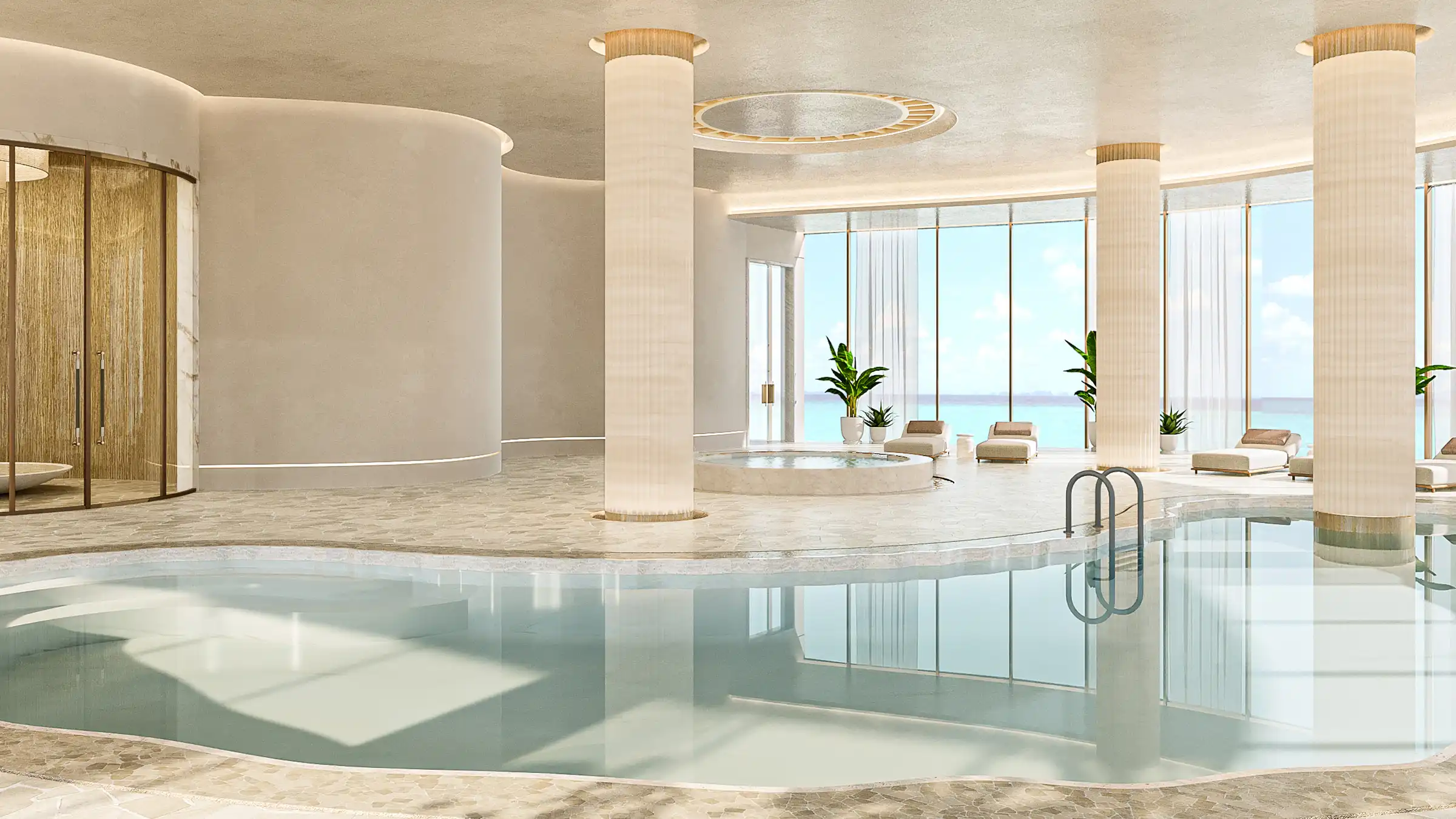 An oceanfront indoor pool surrounded by soft-toned columns and panoramic sea views.